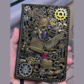 BrassBound Pages Seraphine Nightwing handmade steampunk journal with compass, metal wing, key charm, layered gears and iridescent galaxy stone cover