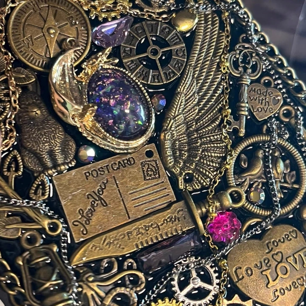 Seraphine Nightwing by BrassBound Pages, close-up of compass clock, metal wing, key charm, zodiac wheel and iridescent galaxy cabochon on a handmade steampunk journal