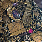 Seraphine Nightwing by BrassBound Pages, close-up of compass clock, metal wing, key charm, zodiac wheel and iridescent galaxy cabochon on a handmade steampunk journal