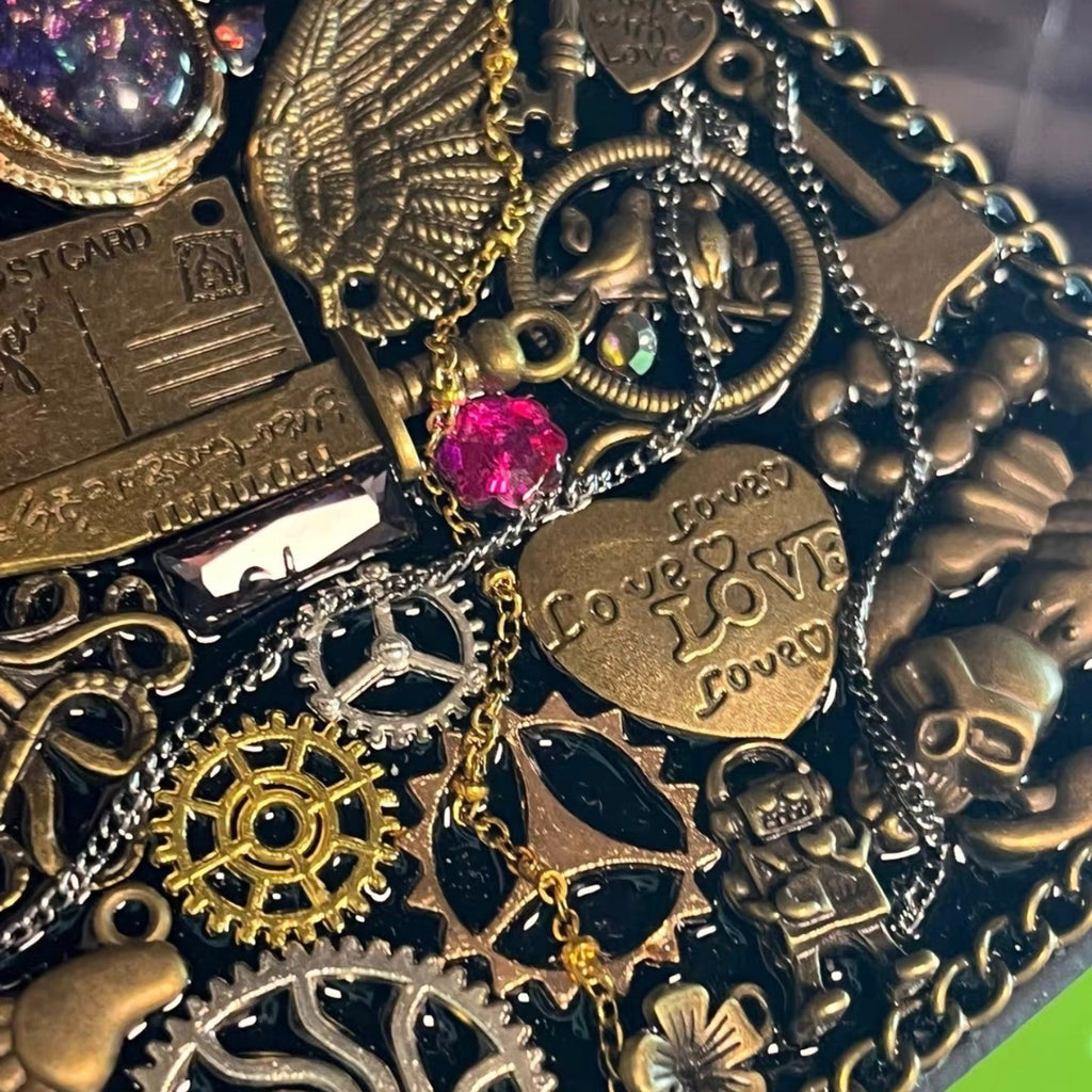 Seraphine Nightwing BrassBound Pages steampunk journal detail with layered gears, “Love” heart plate, pink crystal accent, and scorpion charm on black resin cover