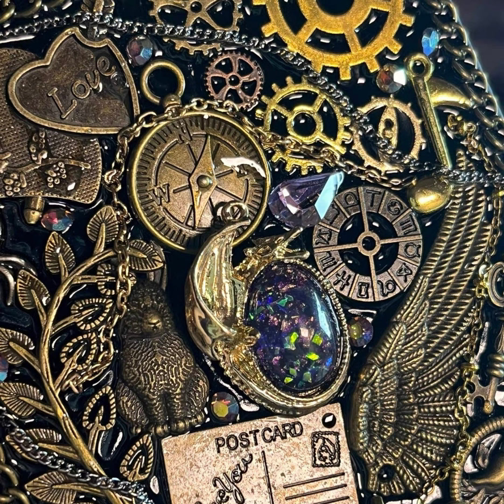 BrassBound Pages Seraphine Nightwing handmade steampunk journal close-up with compass clock, antique gears, wing detail, and iridescent galaxy stone with purple crystal accent
